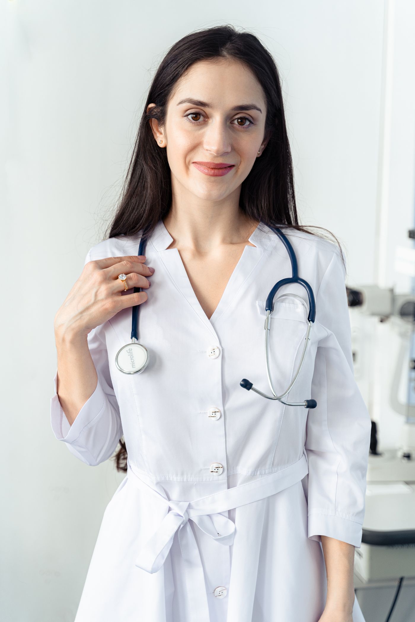 Una doctora de bata blanca, de pie y sonriendo